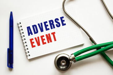 ADVERSE EVENT is written in a notebook on a white table next to pen and a stethoscope.