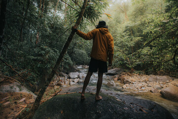 Male traveler explore the beautiful of rainforest stream in the morning.Male traveler camping in the rainforest.Grain effects and tone color applied.