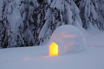Igloo stands on the snowy lawn. Night winter mountain landscapes. House with light. Location place...