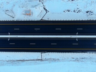 Aerial view black canvas of a new high-speed highway with applied road markings against the background of white snow