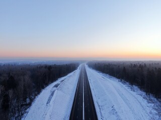 Aerial view of the Central Ring Road (CKAD) at sunrise. Beautiful panoramic landscape of a straight road overlooking the horizon. Travel by car in winter