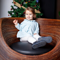 Niña feliz sentada junto al árbol de Navidad