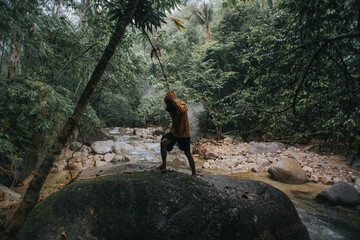 Male traveler explore the beautiful of rainforest stream in the morning.Male traveler camping in the rainforest.Grain effects and tone color applied.