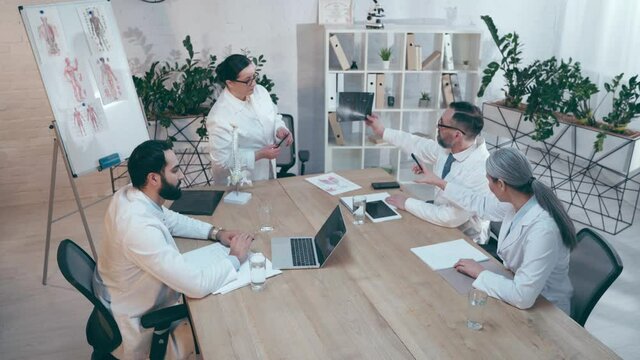 doctor showing x-ray diagnosis on concilium with multiethnic colleagues