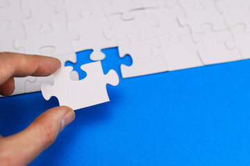 missing piece of the puzzle is inserted by the hand into its place