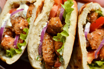 Lavash salad with fried chicken and vegetables. Pita with chicken nuggets, tomatoes, red onions and lettuce and sauce. Healthy fast food. Top view. Closeup