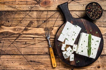 Cut cheese feta with rosemary on a wooden cutting board. wooden background. Top view. Copy space