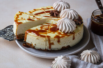 Vanilla cheesecake with carrot cake crust served with salty caramel topping and meringue, light concrete background.