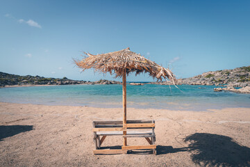 Sitzbank unter einem Sonnenschirm am Strand
