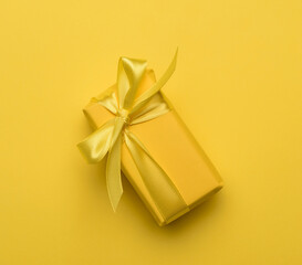 rectangular box with a gift wrapped in yellow paper and tied with a silk yellow ribbon