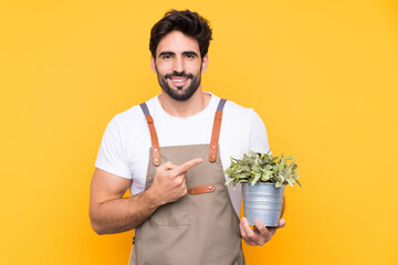 Gardener man with beard over isolated yellow background pointing finger to the side
