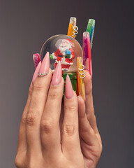 Hands with sculpted nails holding christmas sphere