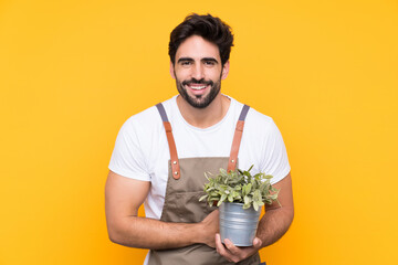 Gardener man with beard over isolated yellow background laughing