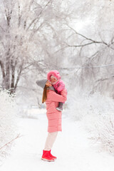 Fototapeta na wymiar Smiling mother lifts her young daughter in pink winter clothes
