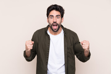 Young handsome man with beard over isolated background celebrating a victory in winner position