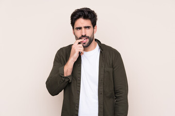 Young handsome man with beard over isolated background nervous and scared