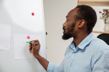 Writing, talking. English courses at home. Smiling african man teaches student, explaining in...