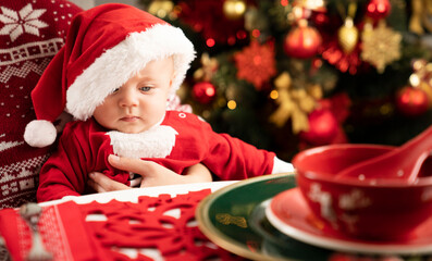 Celebrating Christmas time. Portrait of little Santa Claus on Christmas tree background.