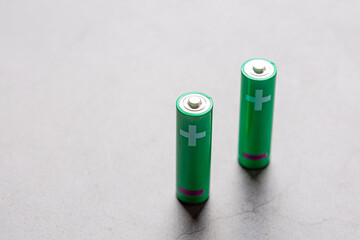 Couple of green double AA batteries isolated on a bright grey background with white positive sign