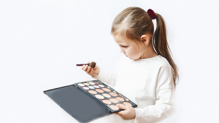 Little caucasian girl playing with cosmetics making makeup on white background. Child's Beauty Concept