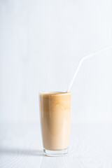 Korean fluffy creamy whipped coffee. Cold dalgonacoffee coffee in a glass on a light background. Iced coffee. object at the bottom of the frame. Copyspace