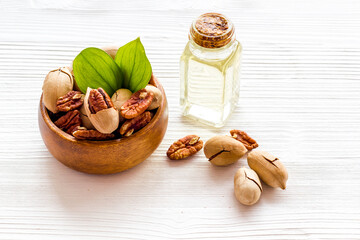 Pecan essential oil in bottle with nuts, close up