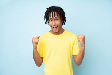 Young african american man isolated on blue background celebrating a victory in winner position