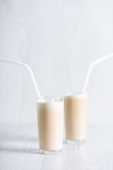 Trendy breakfast. Dalgon coffee. Milkshake with instant coffee and sugar, whipped to a thick foam in glasses with a straw on a light background.