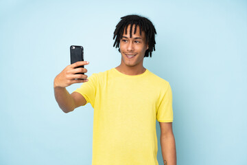 Young african american man isolated on blue background making a selfie