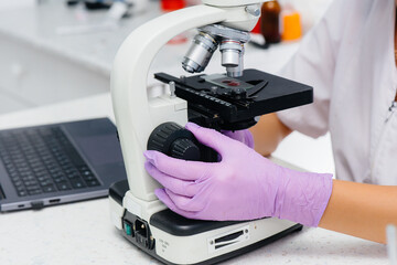 An infectious disease doctor works at a close-up microscope. Study of viruses and bacteria in the medical laboratory