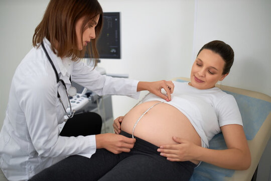 Gynecologist measuring with tape tummy of pregnant woman