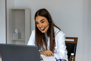 Portrait of a positive female doctor having online consultation in her clinic office with laptop....