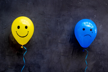Emotions concept. Happiness and depression faces on balloons, top view