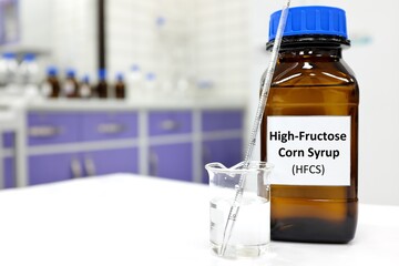 Selective focus of high-fructose corn syrup or hfcs food and beverage sweetener in dark brown glass bottle inside a laboratory.