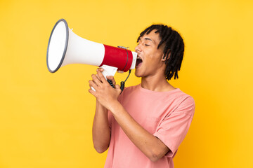 Young african american man isolated on yellow background shouting through a megaphone