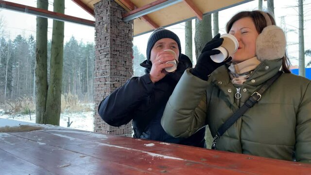 Young couple drinks coffee together outdoor at winter time. Romantic couple. Slow motion.