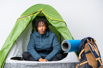 Young african american man inside a camping green tent and looking up