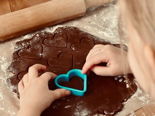 A child's hand makes heart-shaped cookies. Valentine's day. Christmas