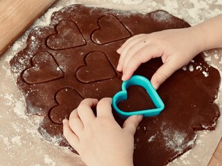 A child's hand makes heart-shaped cookies. Valentine's day. Christmas