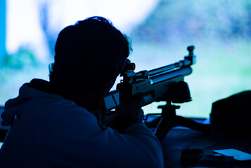 Shooter with sporting air rifle takes aim, at the shooting range.