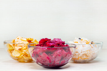 Homemade marinated cabbage kimchi, sauerkraut and beet sauerkraut  sour in glass bowls on white wooden background. Fermented preserved vegetarian food.