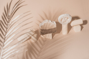 Handmade soap, loofah sponge and geometric shapes.  Sunshade shadow on beige background. Zero...