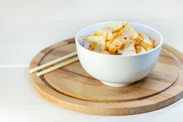 Kimchi cabbage in bowl with chopsticks, Korean food.