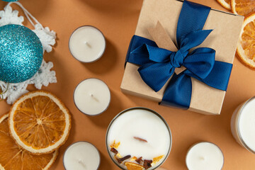 gift in a box with a blue ribbon, white candles, toys for Christmas, blue balls, toys and oranges, close-up.