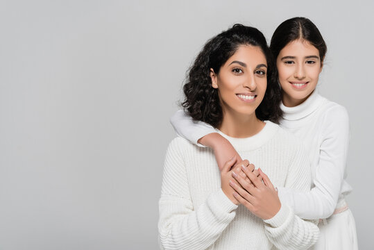 Cheerful Hispanic Child Embracing Mother And Looking At Camera Isolated On Grey, Two Generations Of Women