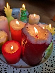Burning multicolored candles stand on a white platter