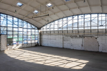 Corner of huge empty industrial warehouse. Modern building hemispherical reinforced concrete load bearing roof. Metal construction.
