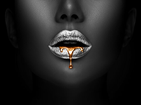 Golden lipstick closeup. Liquid metal dripping from silver lips. Beautiful makeup. Sexy lips, bright liquid paint on beauty model girl's mouth, close-up. Lipstick.