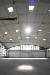 Huge empty industrial warehouse building. White interior. Hemispherical reinforced concrete load bearing roof with windows. Unique architecture.