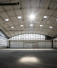 Huge empty industrial warehouse building. White interior. Hemispherical reinforced concrete load bearing roof with windows. Unique architecture.